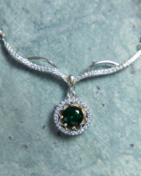 istock Elegant silver necklace with green gemstone sparkling on metallic background 2177114829