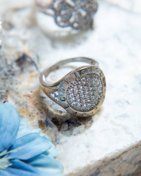 istock Silver ring with diamonds on stone surface with other rings and blue flower 2177114877