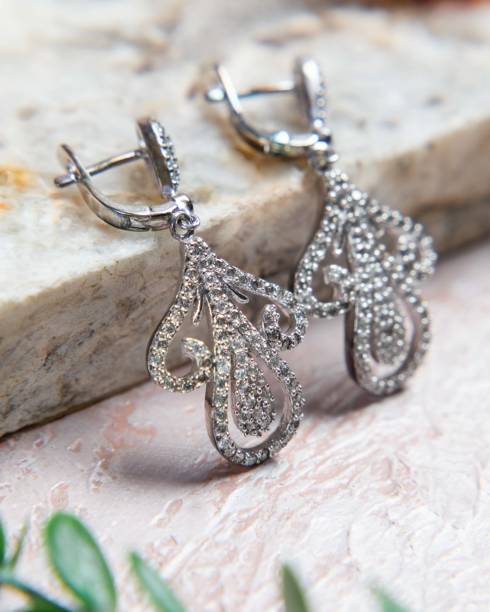 istock Pair of silver diamond earrings resting on stone surface 2177114997
