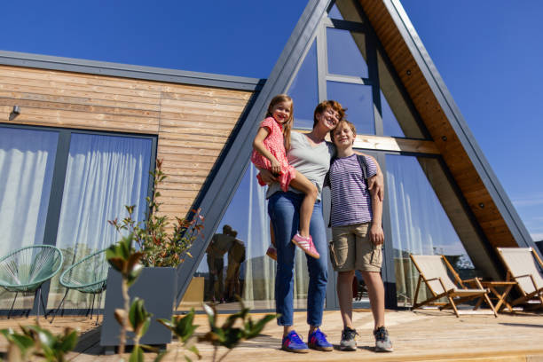 istock Mother and two children in front of A-frame house 2177123805