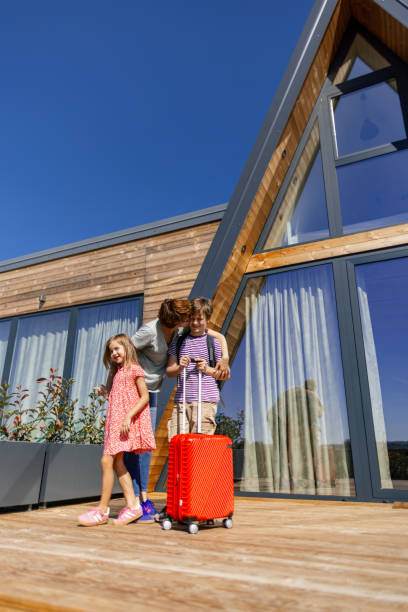 istock Mother and two children in front of A-frame house 2177123810