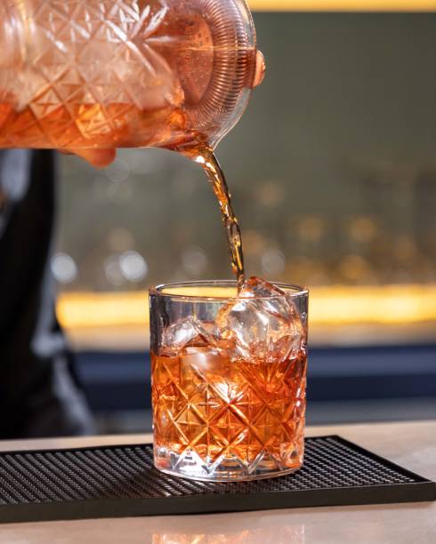 istock Bartender pouring cocktail into crystal tumbler with ice cubes 2177123944