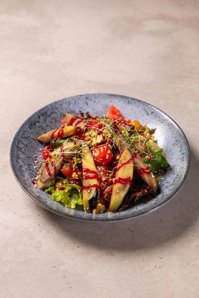 istock Grilled eggplant salad with tomatoes and walnuts sitting on plate 2177124221