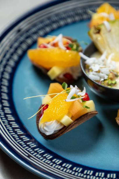 Delicious dessert tacos with fresh fruit and cream filling lying on blue plate