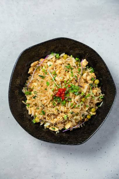istock Steaming fried rice garnished with herbs sitting in black bowl 2177124945