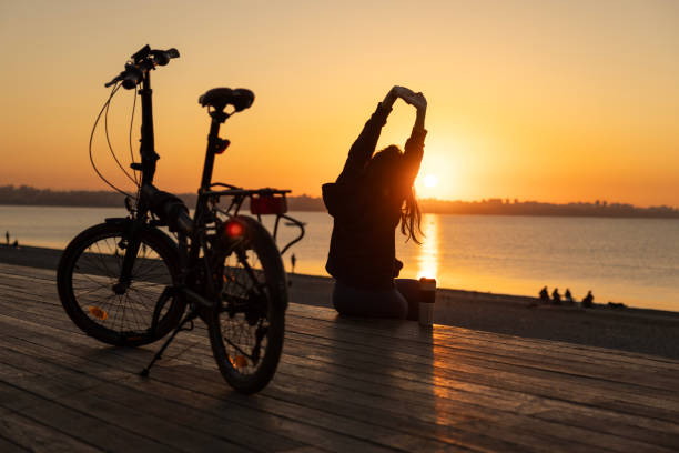 a woman resting on the beach after cycling, a woman resting on the beach after cycling at sunrise