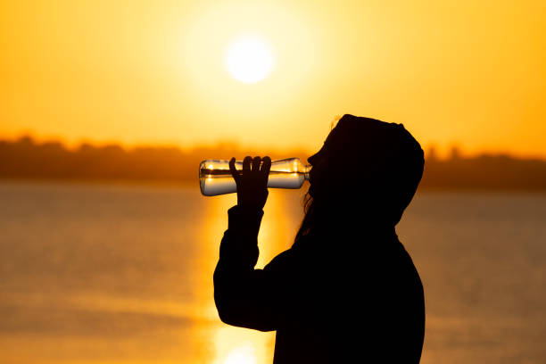 a woman drinking water after exercising on the beach