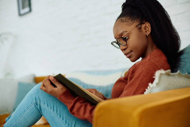 istock Young black woman relaxing on the sofa while reading book. 2177132772