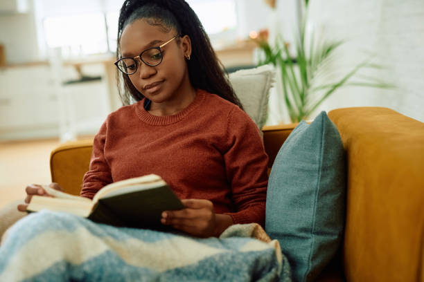 istock Relaxed black woman reading a novel on the sofa. 2177132833