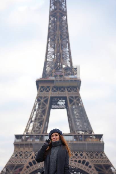 istock Parisian Woman in Beret and Grey Coat Poses on Highway with Eiffel Tower 2177136568