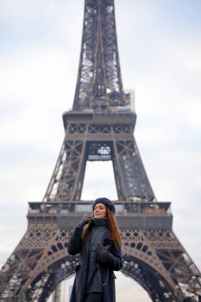 istock Parisian Woman in Beret and Grey Coat Poses on Highway with Eiffel Tower 2177136604