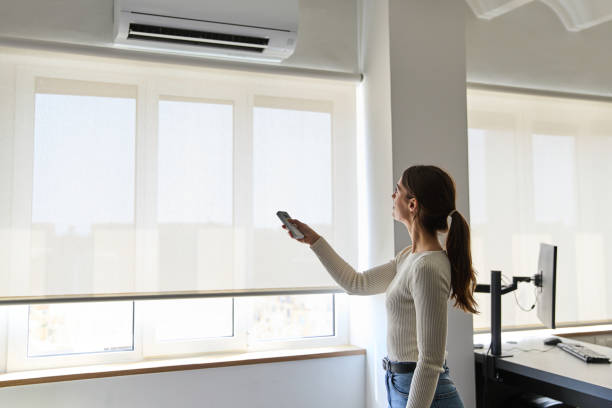 istock Woman pointing remote control to air conditioner at home 2177138703
