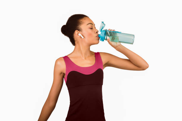 istock Fit Afro Girl Drinking Water Standing Over White Studio Background 2177139972