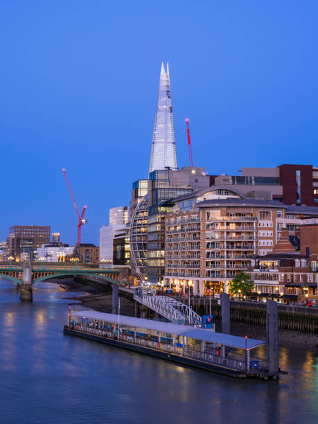 London, United Kingdom - June 25, 2024: A vibrant cityscape of London featuring modern skyscrapers along the River Thames, blue hour time.