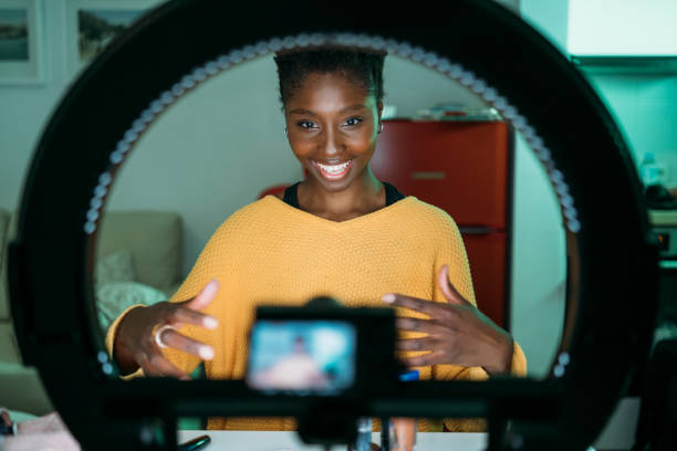 istock A content creator is in her kitchen, smiling, as she uses a ring light to film a video 2177147041