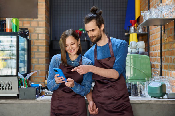 istock Young man and woman restaurant coffee shop workers using smartphone together 2177147344