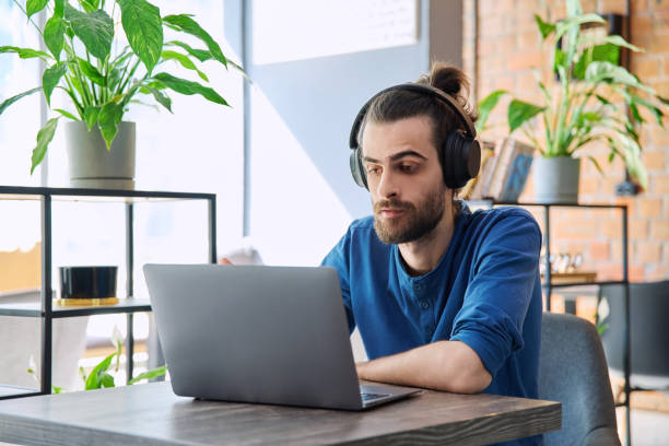 istock Young handsome man in headphones having work video chat using laptop 2177147390