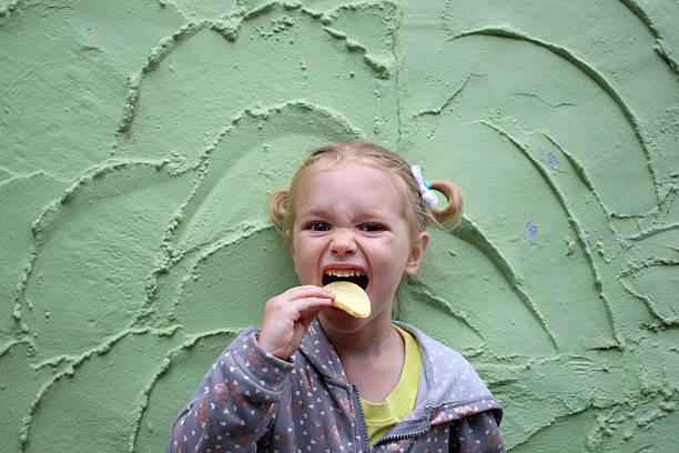 A joyful little girl smiles brightly, with colorful ice cream smeared across her face, capturing the essence of pure, carefree happiness