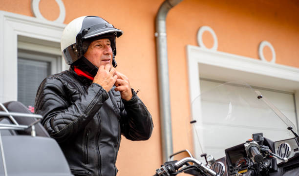 istock Older Man Adjusting Helmet Next to Motorcycle 2177154276