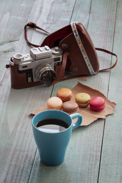 Cup of coffee and a macaron vintage camera in background