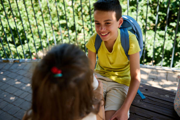 istock Smiling boy with backpack talking to friend in park 2177163597