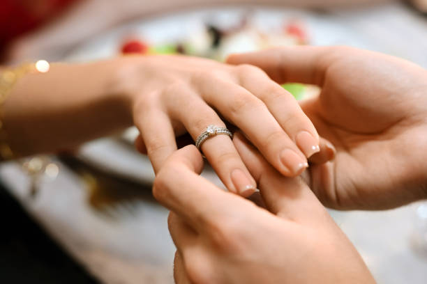 istock Man Putting Engagement Ring On Girlfriend's Hand During Dinner In Restaurant 2177163645