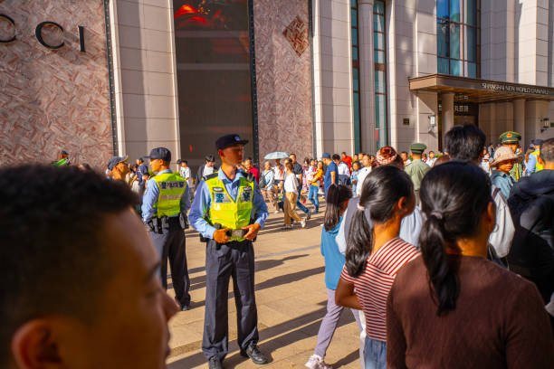 Tarragona, Spain - March 29, 2024: Two back-facing civil protection officers watch over a crowd during an outdoor event on a busy street ensuring safety and order.