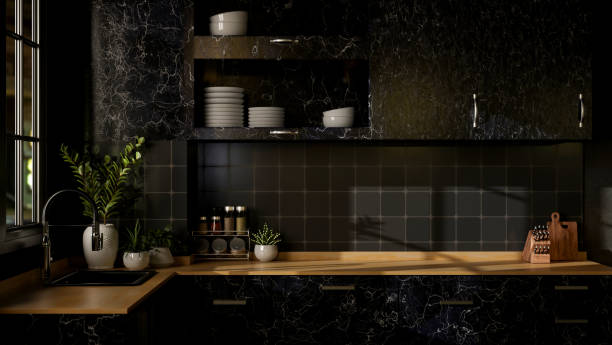 Interior design of a modern black kitchen features a black marble kitchen counter with a wooden top.