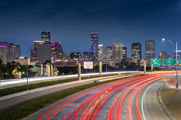 Houston downtown with car vehicle light tail on highway traffic to downtown district at night with skyscraper modern business office in center of Houston city in Texas, USA, United States of America at night