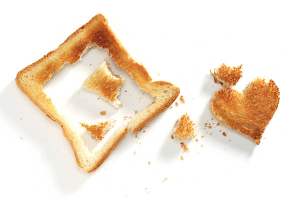 Slice of toasted bread with a heart-shaped cutout on a white background, top view