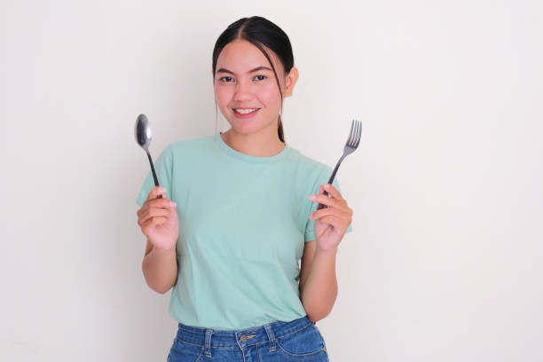 istock A woman smiling happy while holding dinning spoon and fork 2177185584