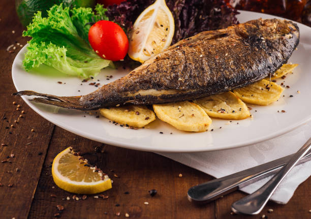 Close-up of baked trout fish with potato and lemon on a plate in a fish restaurant