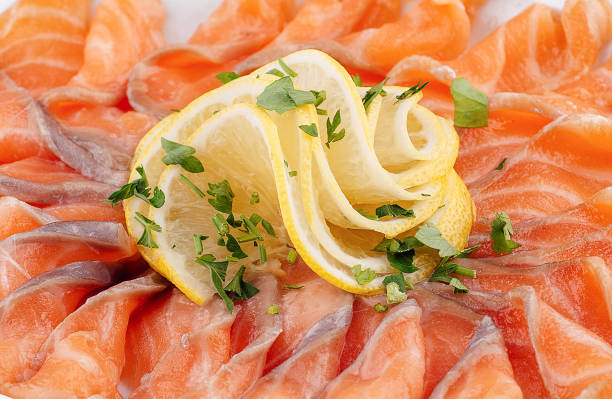 Sliced salmon dish beautifully arranged on a plate and garnished with lemon and herbs