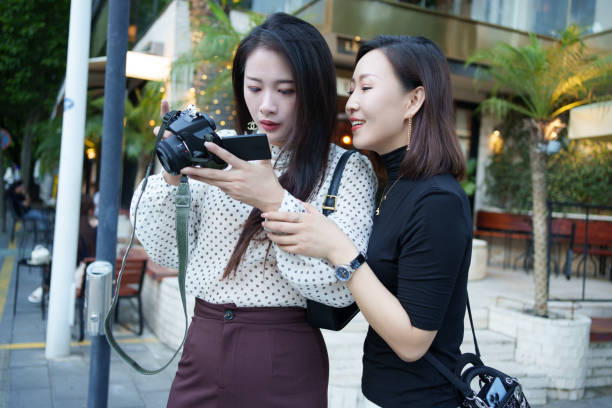 Two female tourists are looking at camera photos