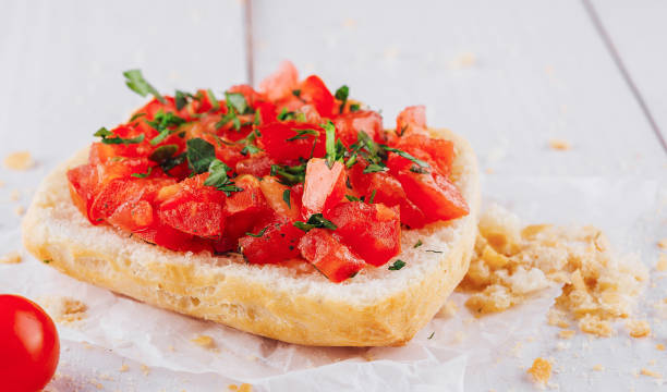 istock Delicious bruschetta with chopped tomatoes and basil resting on paper on white table 2177187818