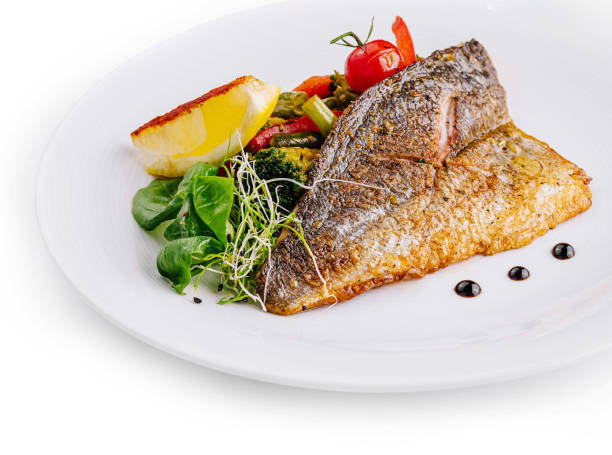 istock Delicious grilled fish with vegetables and lemon on white plate 2177189512