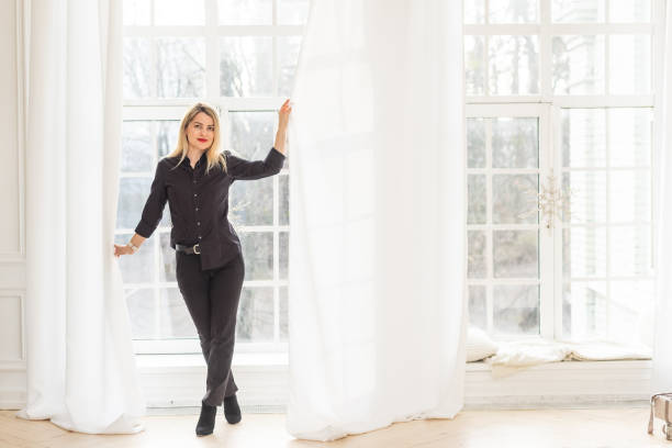 istock Young woman opening window curtains at home 2177190412