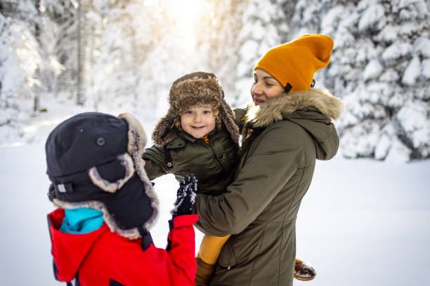 A mother and her boys enjoy a playful winter day on a snowy mountain.