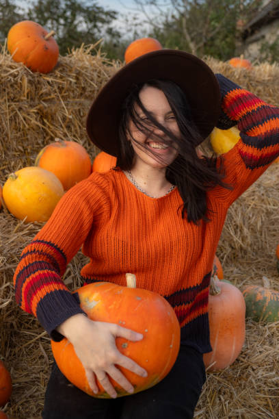 istock Woman holding a pumpkin sitting on hay bales 2177190817