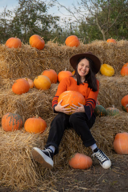 istock Woman holding a pumpkin sitting on hay bales 2177190823