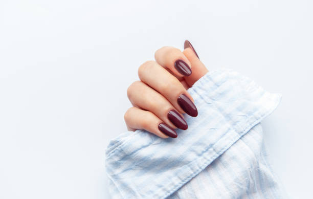 istock Elegant hand showcasing dark maroon oval nails resting on a light blue fabric, perfect for a stylish manicure moment 2177191367