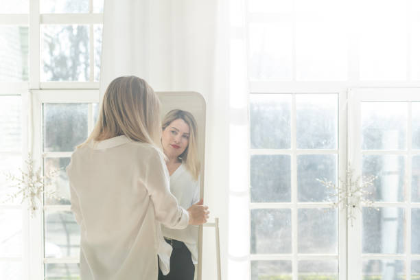 istock Self-confident Woman looking at her reflection into the mirror indoors. Beautiful interior design 2177191706