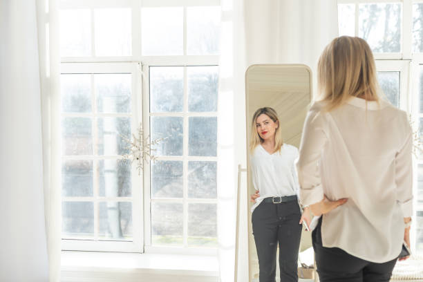 istock Self-confident Woman looking at her reflection into the mirror indoors. Beautiful interior design 2177192356