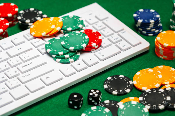 istock Chips and playing cards on a green felt surface near a computer keyboard during an online gaming session at home 2177192521