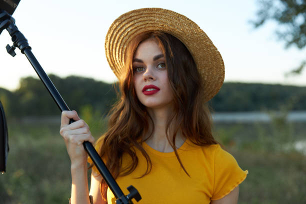 pretty woman red lips camera tripod hat nature. High quality photo