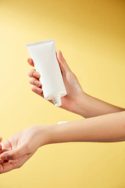 istock Perfect for sunscreen advertising, this minimalist image shows a model applying an unlabeled white tube of cream to her wrist against a brilliant orange background that mimics the sun. 2177196482