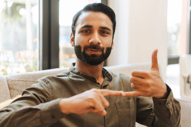 istock Confident indian deaf man sitting on couch in office, speaking with sign language, looking at camera 2177197197