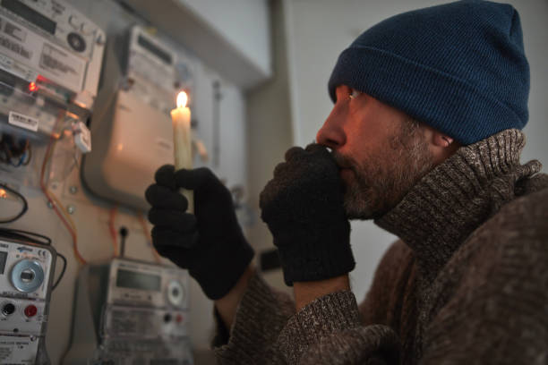 istock Checking the electricity power meter with a candle in cold winter days while there is power outage. 2177197638