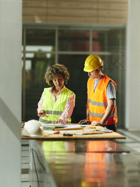 istock Female inspector working on plans with manual worker in construction building. 2177198375