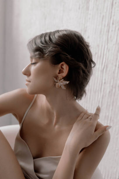 istock A young woman sits gracefully by a window, showcasing elegant earrings while lost in thought. The soft light enhances her calm demeanor and stylish ambiance in the room 2177200222